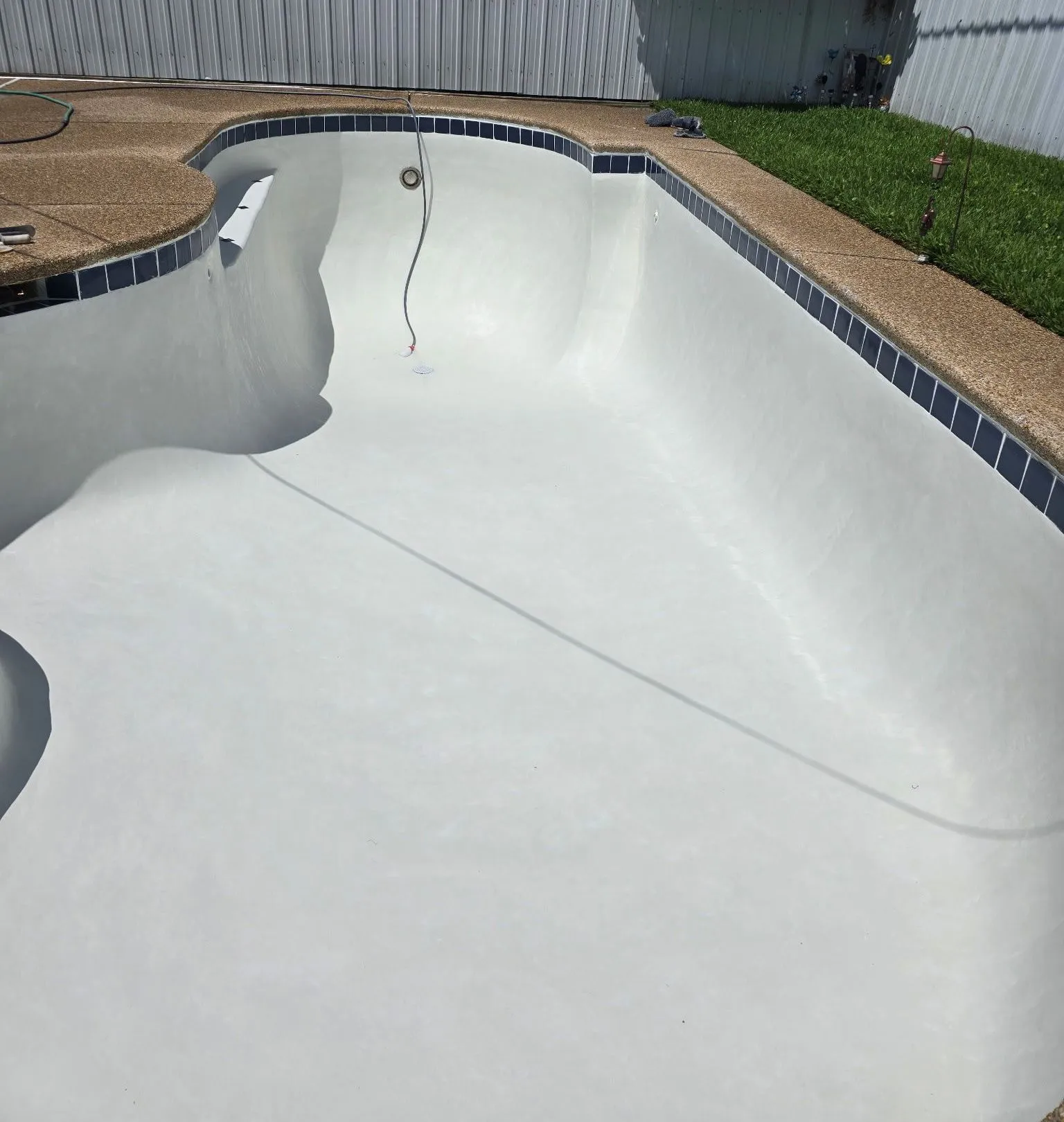 An empty swimming pool with a house in the background
